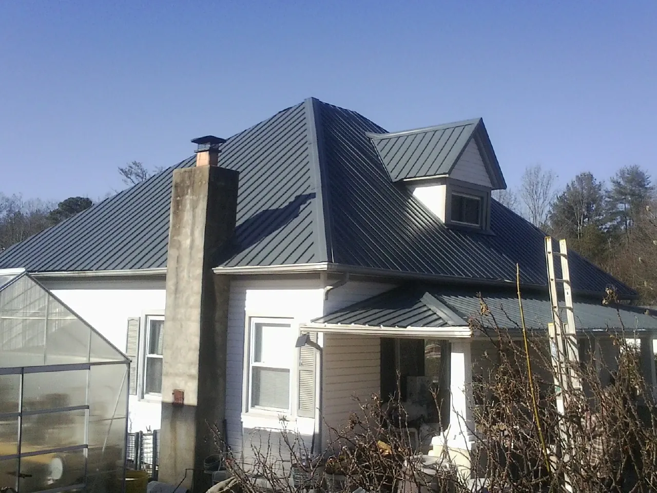 Dark blue standing seam metal roof on a white farmhouse with dormer — Slate & Tile Roof Repair by Roofing Brothers in Haworth