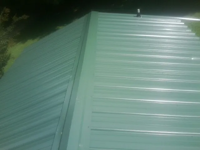 New green metal panels meeting at the ridge of a roof — Flat Roof Repair work by our crew in Haworth