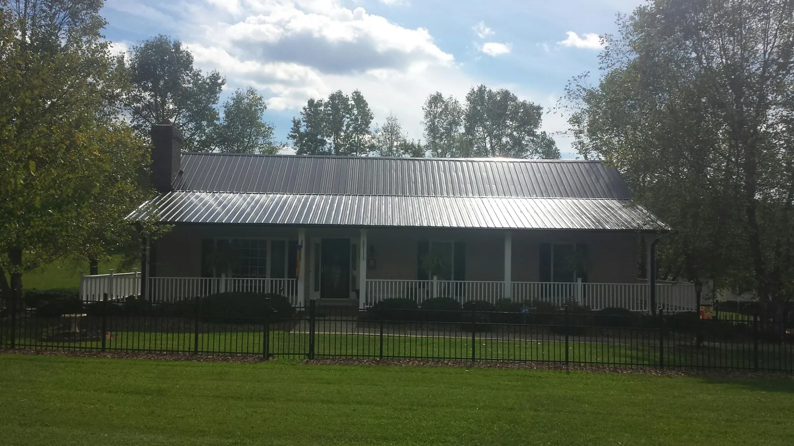 Gray metal roof on a brick ranch with a full width front porch — Gutter Guard Installation work by our crew in Haworth
