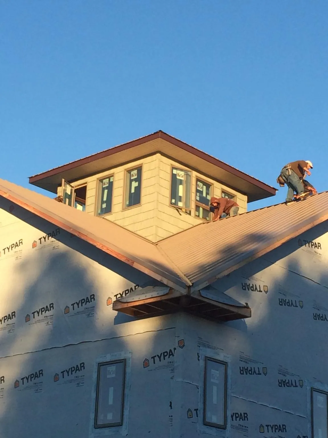Roofers working around a rooftop cupola on a new metal roof at sunset — Roof Waterproofing in Haworth by Roofing Brothers